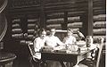 Photograph of three of Nevins Memorial Library's earliest librarians. Seated at the table in the Reference Room are: Miss Alice Chase, Miss Crosby and Miss Tooday Dorsey. Reference books are in the background and artifacts from the Nevins Historic Collection (Pheasant, Vase, Table and Richsonian Chair) are visible.[6]