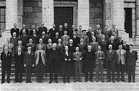 Around thirty men standing on steps.