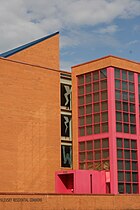 An orange brick building with pink window frames and a blue roof