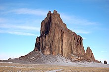 Solid rock spire protruding from the desert.