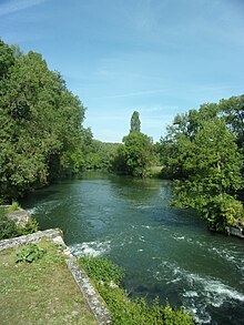 Photographie en couleurs d'un cours d'eau coulant entre deux rives arborées.