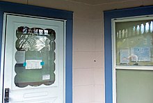 Outer door and window of a house with several paper notices taped to both of them