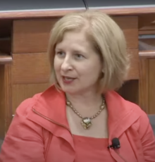 Ann Marie Lipinski in a lecture hall wearing a pink suit and gold necklace