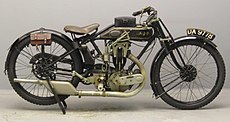 AJS Model E6 uit 1925. Het is zo licht mogelijk gebouwd, dus zonder bagagedrager (die wel leverbaar was). Daarom hangen de gereedschapstasjes aan het achterspatbord. De rijder heeft een extra tasje op de tank, dat als kussentje dient als hij in "racehouding" zit.