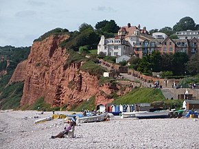 Petite baie, plage de galets, village coquet perché sur une grande falaise de terre rouge.