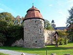 Wehrturm mit Stadtmauer und Pfarrkirche im Hintergrund