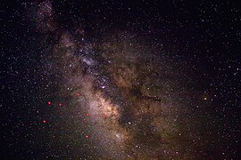 Uma visão do céu noturno perto de Sagittarius, aprimorada para mostrar melhor contraste e detalhes nas faixas de poeira. As principais estrelas em Sagittarius são indicadas em vermelho