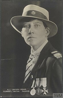 Photographie d'une femme de profil avec les cheveux courts en uniforme portant un chapeau et trois médailles.