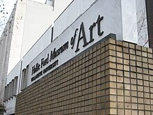 Close up of the museums name on the wall above square-shaped earth-tone bricks.