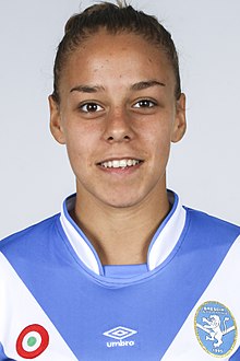 Headshot of woman in a blue and white kit