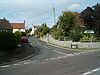 Street scene showing road junction with houses and cars