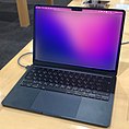 A MacBook Air, in midnight color, on a wooden desk.