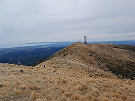 Image a mountain from a nearby hill on an overcast day, with a view over the city of Christchurch in the background