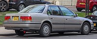 Rear three-quarter view of a four-door car with a three-box body style.