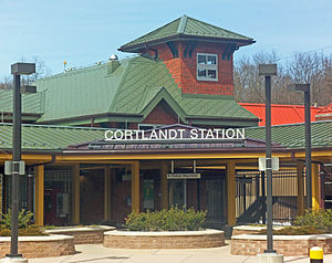 A complex brick building with pointed green roofs and a large sign in the middle saying "Cortlandt Station"