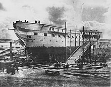 A photograph of a ship out of the water and under repair