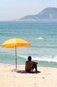 Nak lanang sané duduk ring betén parasol.