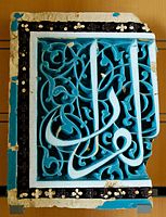 Part of a 15th-century ceramic panel from Samarkand with white calligraphy on a blue arabesque background.