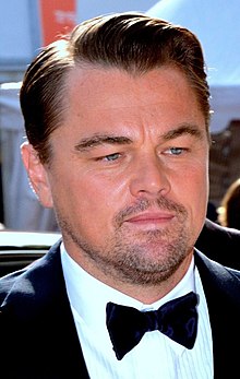 Leonardo DiCaprio looking away from the camera, wearing a tuxedo on the red carpet