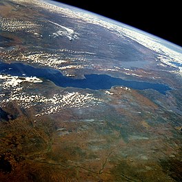 Satellite image of Lake Tanganyika on Earth in center and left, space in upper right.