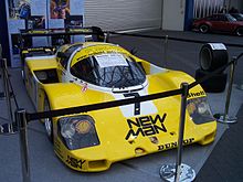 Photographie en couleur d'une voiture d'endurance majoritairement jaune, vue de trois-quarts gauche, lors d'une exposition.