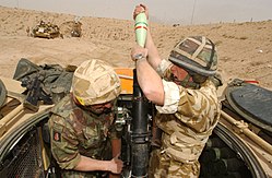 Two soldiers with a mortar gun—one loading and the other aiming