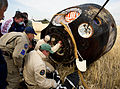 Russian support personnel assist crew members in leaving the capsule.