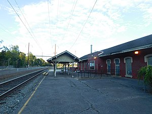 A brick railway station with a wide platform and wooden canopy