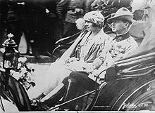 Photo d'un jeune couple dans une voiture découverte.