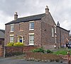 A brick house with the chapel extending behind it