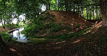 Motte castrale située à Péré : tertre arboré avec autour un fossé partiellement à sec.