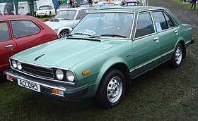 Front three-quarter view of a front-engined four-door car with a three-box body style whose luggage compartment is separate from the passenger cockpit.