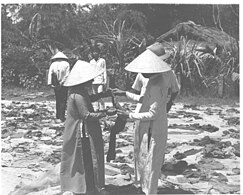 Bits of tattered clothing, sandals and slippers are examined by Vietnamese women who lost relatives in the 1968 Huế massacre