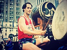 A marathon runner with a red shirt playing taiko drums after finishing the marathon