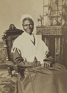 Photographie noir et blanc d'une femme noire assise dans un fauteuil