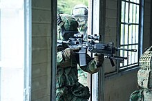 A soldier entering a house with the Colt IAR.