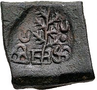 A coin of Takshashila, portrays a tree flanked by a hill surmounted by a crescent and a Nandipada above a swastika.[28]