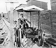 An electric-powered flume cart raises boards to the tops of the drying piles.: 101