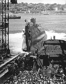 From an inclined launching slipway, Triton slides into the water, creating a large disturbance.