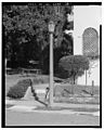 Street lamps are octagonal ornamental metal housings atop hexagonal cast red concrete with granite aggregate columns