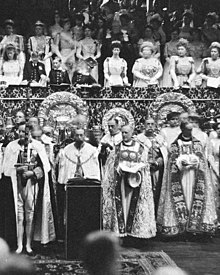 Black-and-white photograph of large altar dishes standing on a table in front of the royal box during a coronation