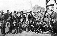 Des soldats en uniforme, posant avec des hommes en armes coiffés de toques de fourrure.