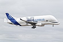 Photo d'un Beluga XL en vol, avec le train d'atterrissage sorti. "Airbus Beluga XL" est inscrit sur la carlingue de l'avion.