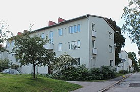 Un bâtiment à trois étages, blanc. En fond, on en voit d'autres similaires.