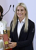 Profile of Putellas holding a trophy bearing a small medal of the Four Bars.