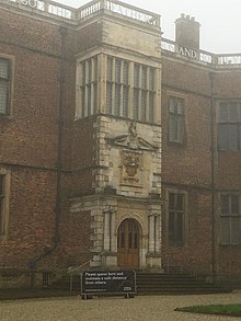 Photograph of entrance porch of Temple Newsam House, Leeds, showing at top the word 'FATHER', below a mullioned window, below a raised portico with coat of arms above a doorway flanked by two Ionic columns on each side.