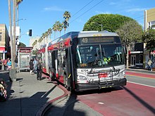 A bus at a bus stop with red pavement