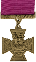 A bronze cross pattée bearing the crown of Saint Edward surmounted by a lion with the inscription "FOR VALOUR". A crimson ribbon is attached.