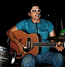 Adkins playing guitar, singing, surrounded by his drumkit