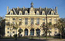 Un grand bâtiment parisien en pierre de taille blonde.